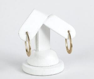 Gold hoop earrings on white display stand.