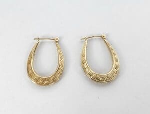 Gold hoop earrings with intricate patterns.