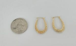 Gold hoop earrings beside a quarter coin.