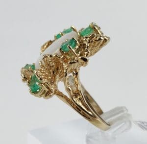 Gold ring with green gemstones and pearl.