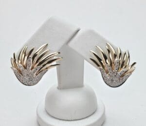Gold and silver earrings on display stand.