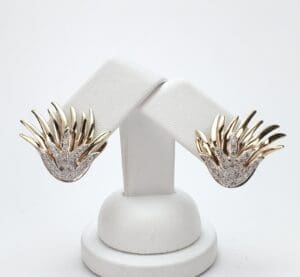 Gold and silver earrings on display stand.