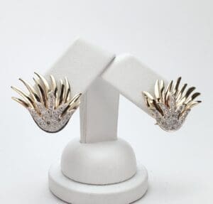 Gold and silver earrings on display stand.