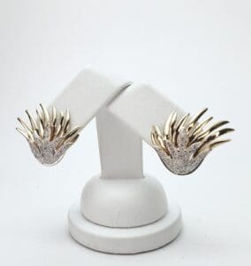 Gold and silver earrings on display stand.