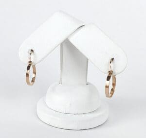 Gold hoop earrings on white stand.