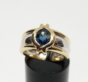 Gold ring with blue gemstone on display.