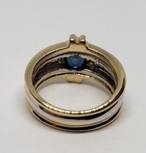 Gold ring with blue gemstone inside band.