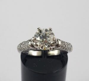 Diamond engagement ring on black stand.