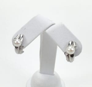 Pearl and diamond earrings on display stand.