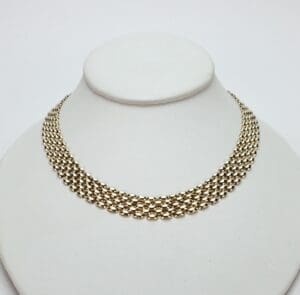 Gold chain necklace on a display stand.