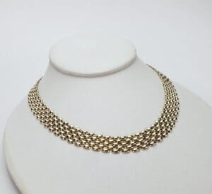 Gold chain necklace on display stand.