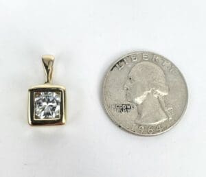 Gold pendant with diamond next to coin.