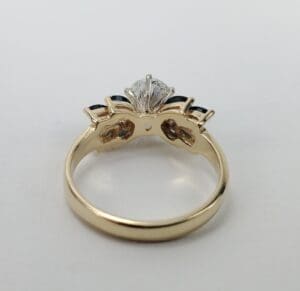 Gold ring with diamond and dark gemstones.