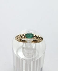 Gold ring with green stone on display.
