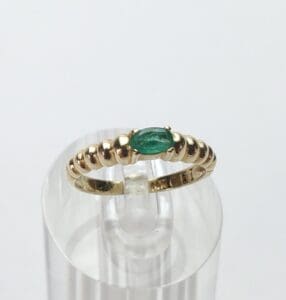 Gold ring with green gemstone on stand.