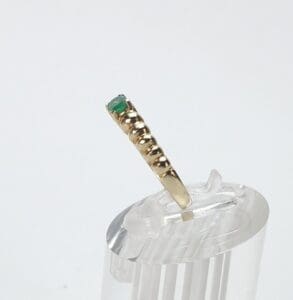 Gold ring with green gemstone on stand.