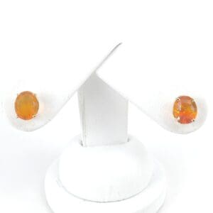 Orange gemstone earrings on white display stand.