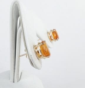 Amber gemstone earrings on white display stand.