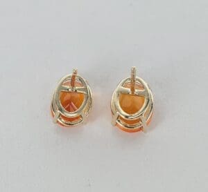 Gold earrings with orange gemstones on white.