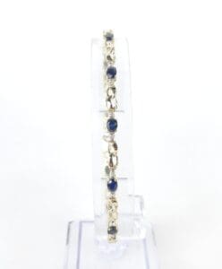Silver bracelet with blue gemstones displayed upright.