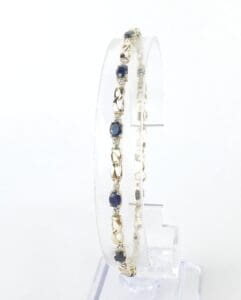 Gold bracelet with blue gemstones display.