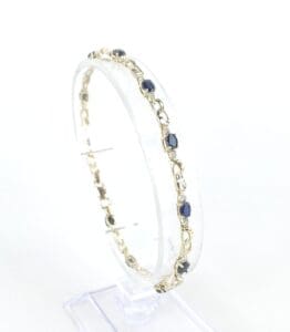 Gold bracelet with blue gemstones displayed upright.