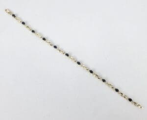 Gold bracelet with black gemstones on white.