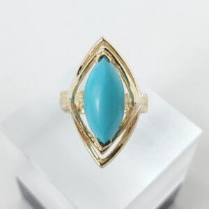 Gold ring with turquoise stone, geometric design.