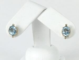 Blue gemstone earrings on white display stand.