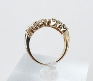 Gold ring with textured design on stand.
