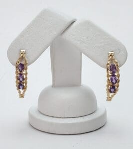 Gold earrings with purple gemstones on display.