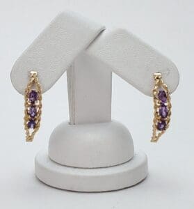 Gold earrings with purple gemstones on display.