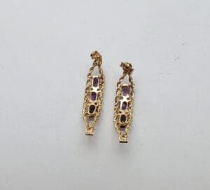 Gold earrings with purple gemstones displayed.