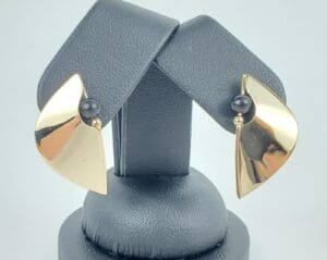 Gold earrings with black bead accents displayed.