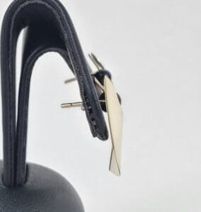 Gold earring on black leather display.