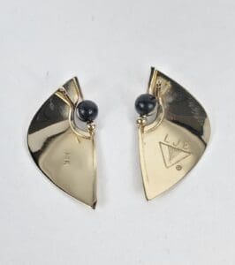 Gold earrings with black beads and engravings.