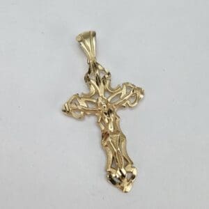 Gold crucifix pendant on white background.