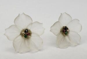 White flower earrings with colorful gemstone centers.