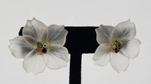 White floral earrings with colorful gemstone centers.