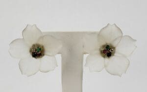 White flower earrings with colorful gemstone centers.
