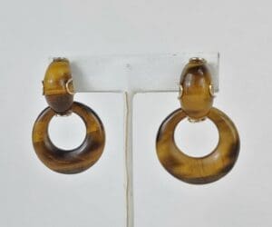 Brown hoop earrings on display stand.