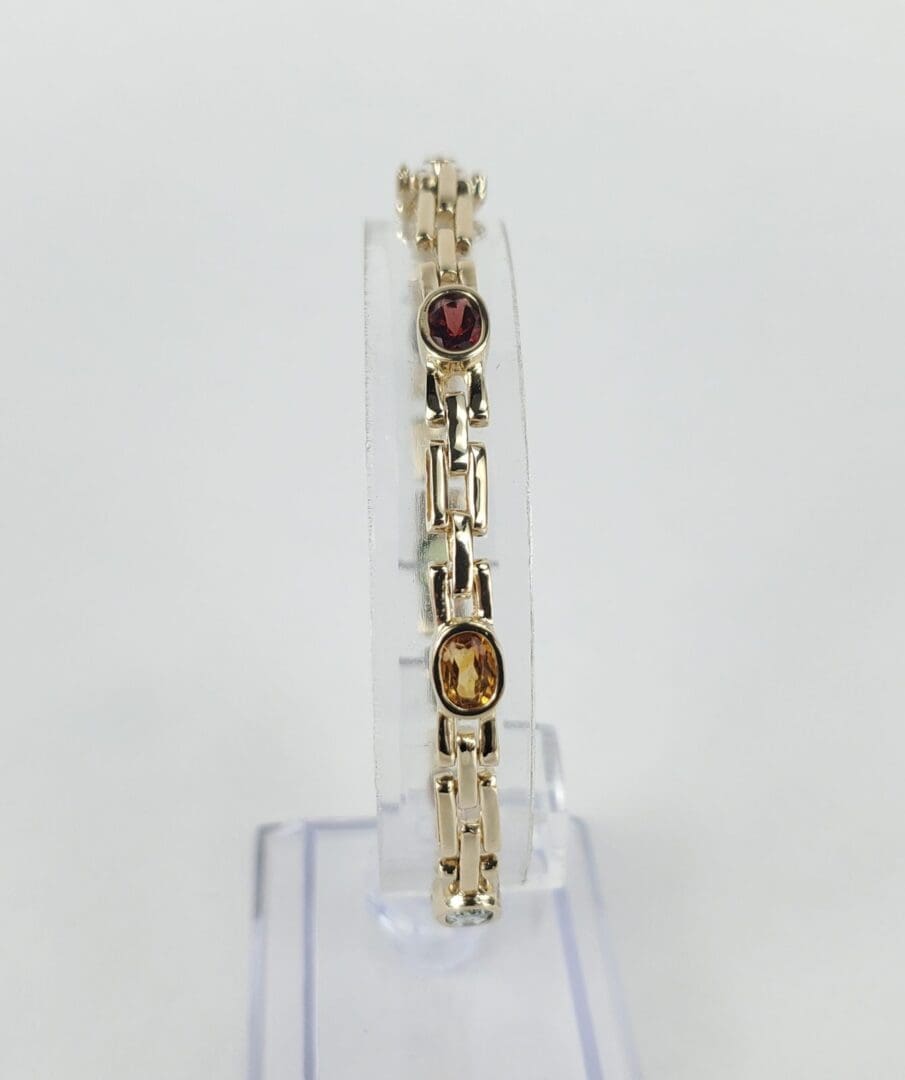 Gold bracelet with red and yellow stones.