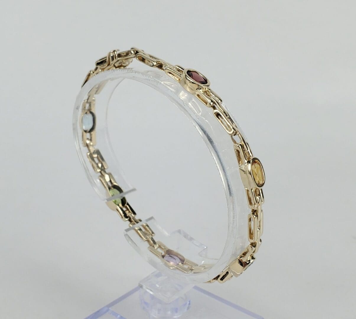 Gold bracelet with colorful gemstones on display.