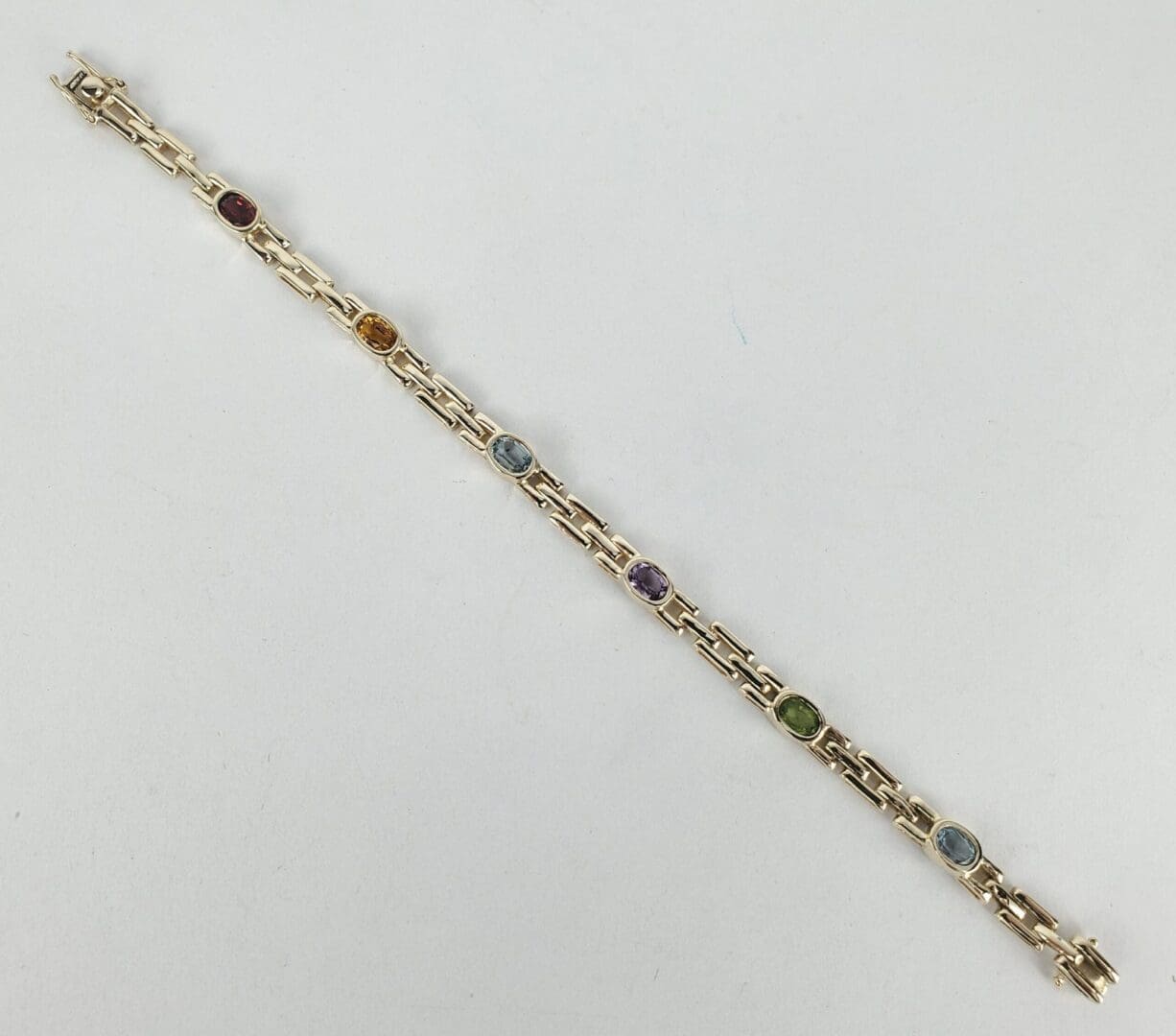 Gold bracelet with colorful gemstone links.