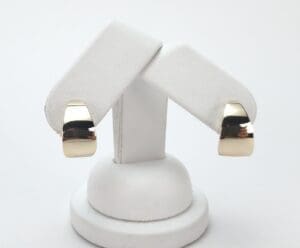 Gold hoop earrings on white display stand.