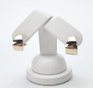 Gold earrings on white display stand.