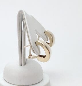 Gold hoop earrings on white display stand.