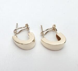 Gold half-hoop earrings on white background.