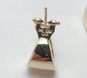 Gold earring with engraved markings.