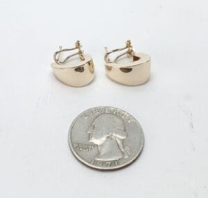 Gold hoop earrings with a quarter coin.